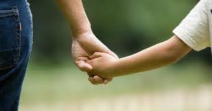 parent holds hand of young child while walking outside Helland & Hurwitz Attorneys at Law Colorado