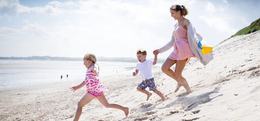 mother and two young children run in the sand toward the water Helland & Hurwitz Attorneys at Law Colorado