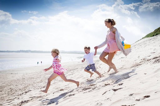 mother and two young children run in the sand toward the water Helland & Hurwitz Attorneys at Law Colorado