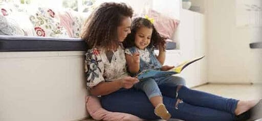 mother reads book to daughter while sitting on the floor in her home Helland & Hurwitz Attorneys at Law Colorado