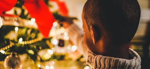 young boy puts holiday decorations on tree Helland & Hurwitz Attorneys at Law Colorado