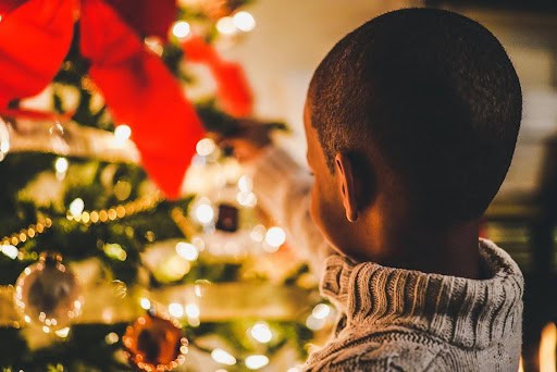 young boy puts holiday decorations on tree Helland & Hurwitz Attorneys at Law Colorado