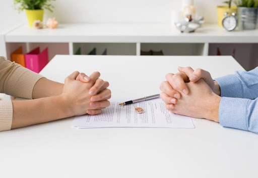 two people sit at table with hands folded with maintenance paperwork between them Helland & Hurwitz Attorneys at Law Colorado
