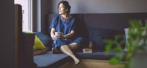 woman sits on couch thinking about her high net worth pending divorce Helland & Hurwitz Attorneys at Law Colorado