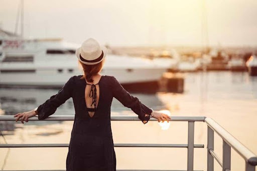 woman wearing hat looks toward harbor and a boat wondering about her high asset divorce Helland & Hurwitz Attorneys at Law Colorado