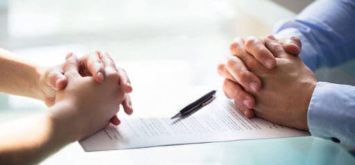 man and woman sit across from table with folded hands as they file for separation Helland & Hurwitz Attorneys at Law Colorado