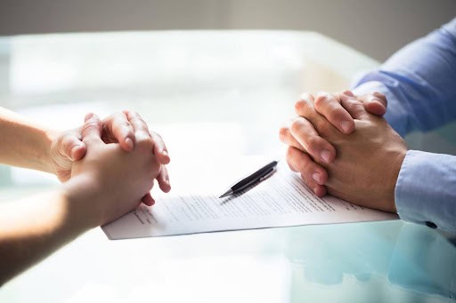 man and woman sit across from table with folded hands as they file for separation Helland & Hurwitz Attorneys at Law Colorado