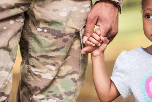 young child holds finger of her father who is in the military Helland & Hurwitz Attorneys at Law Colorado