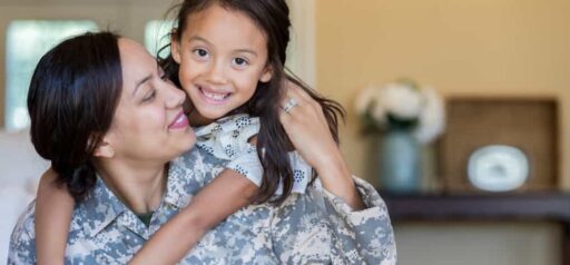 woman wearing military fatigues looks at daughter who is hugging her from her back Helland & Hurwitz Attorneys at Law Colorado