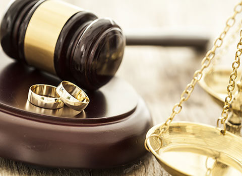 close up of wedding rings near gavel with legal scale in background Helland & Hurwitz Attorneys at Law Colorado