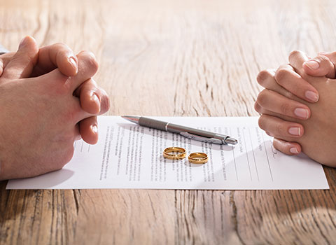 man and woman getting divorced place rings on legal paperwork Helland & Hurwitz Attorneys at Law Colorado