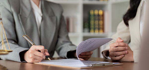 woman signs spousal maintenance paperwork in law office Helland & Hurwitz Attorneys at Law Colorado