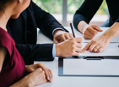 mediator points to signature area for man to sign legal papers Helland & Hurwitz Attorneys at Law Colorado