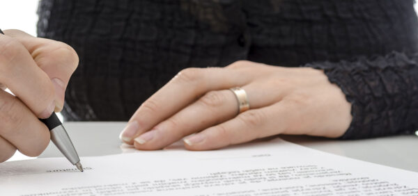 hero image of woman signing legal document Helland & Hurwitz Attorneys at Law Colorado