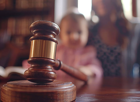 close up of gavel with mother and baby in background Helland & Hurwitz Attorneys at Law Colorado