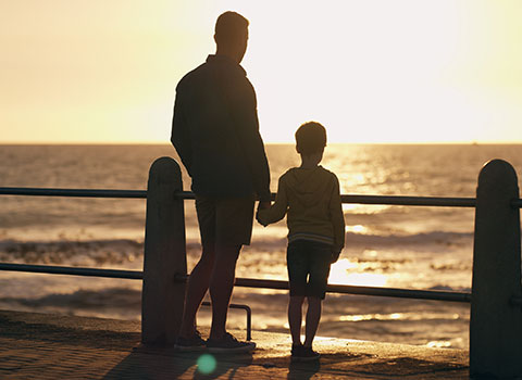 hero size image of father and son holding hands while watching sun set along beach Helland & Hurwitz Attorneys at Law Colorado