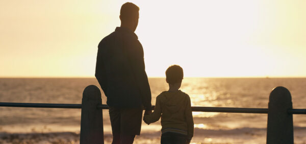 hero size image of father and son holding hands while watching sun set along beach Helland & Hurwitz Attorneys at Law Colorado