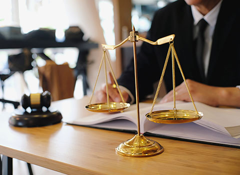 lawyer sits at desk with legal scale in foreground Helland & Hurwitz Attorneys at Law Colorado
