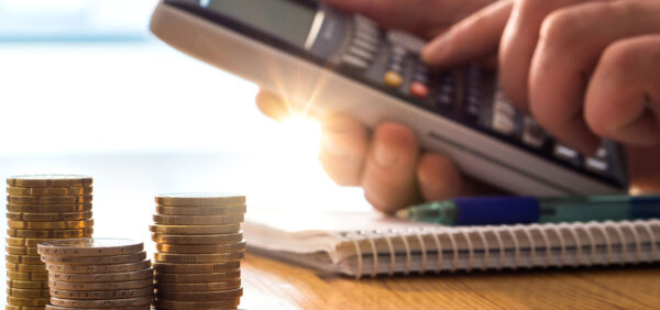 person using calculator with coins on table Helland & Hurwitz Attorneys at Law Colorado