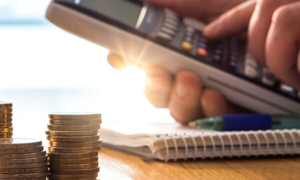 person using calculator with coins on table Helland & Hurwitz Attorneys at Law Colorado