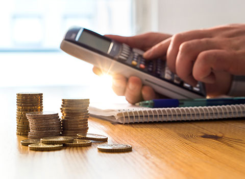 person using calculator with coins on table Helland & Hurwitz Attorneys at Law Colorado