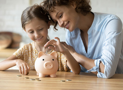 mom teaches daughter to save money using piggybank Helland & Hurwitz Attorneys at Law Colorado